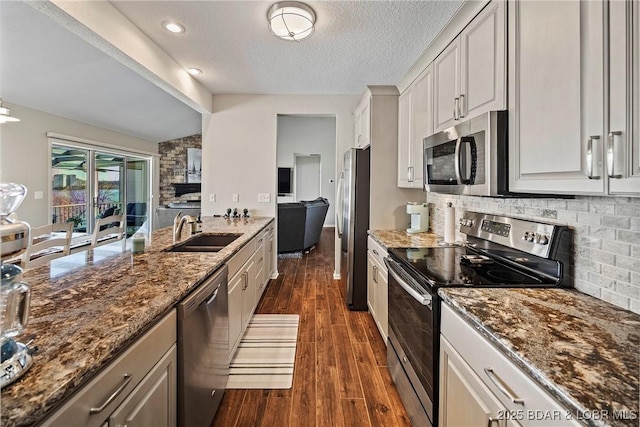 kitchen with sink, white cabinetry, tasteful backsplash, dark stone countertops, and stainless steel appliances