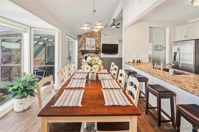 dining room featuring sink, dark wood-type flooring, vaulted ceiling, and a chandelier