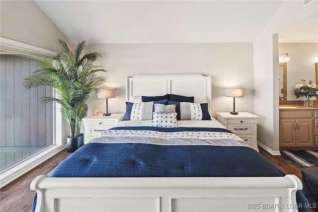 bedroom with vaulted ceiling, connected bathroom, dark hardwood / wood-style floors, and sink