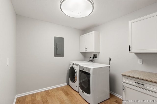 clothes washing area with cabinets, washing machine and clothes dryer, electric panel, and light hardwood / wood-style floors