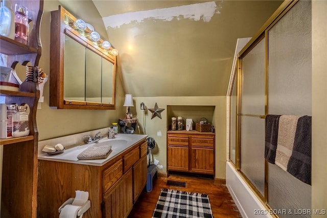 bathroom with vaulted ceiling, combined bath / shower with glass door, hardwood / wood-style floors, and vanity