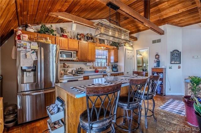 kitchen featuring lofted ceiling with beams, visible vents, stainless steel appliances, a kitchen island, and wood ceiling