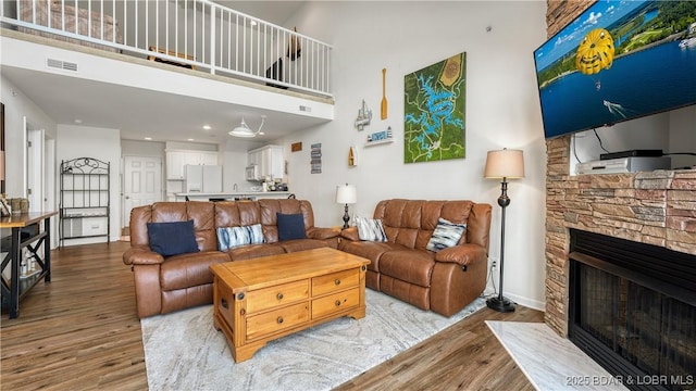 living room featuring a fireplace, light hardwood / wood-style floors, and a high ceiling