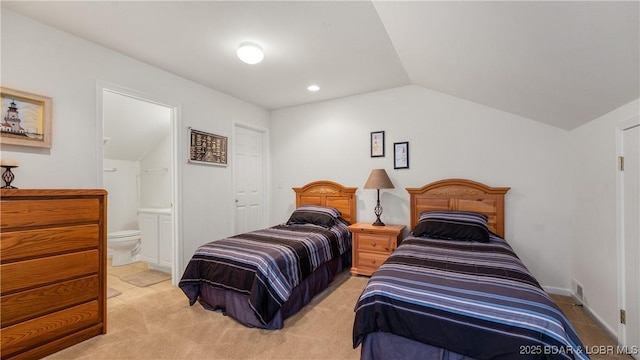 bedroom with light carpet, vaulted ceiling, and ensuite bathroom