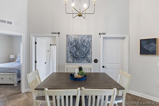 dining space featuring a towering ceiling and a notable chandelier