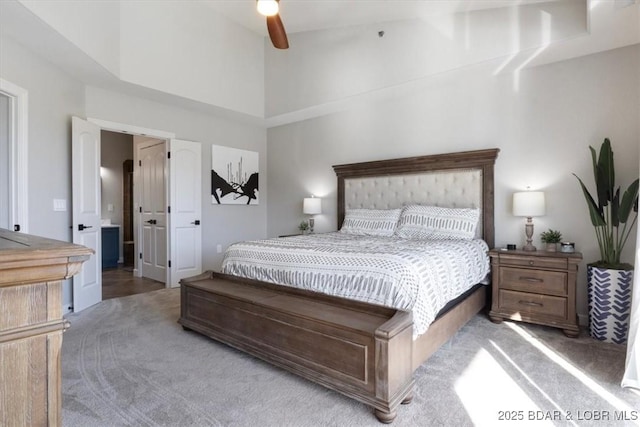 carpeted bedroom with ceiling fan and a high ceiling