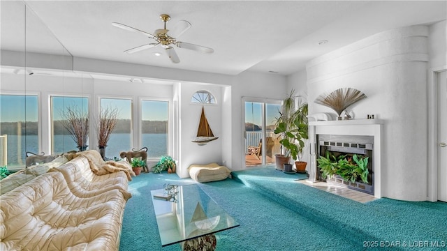 unfurnished living room featuring a water view, carpet, and ceiling fan