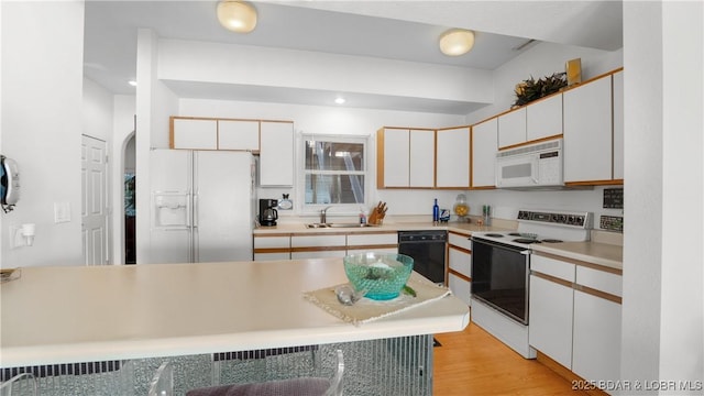 kitchen featuring white cabinetry, sink, white appliances, and light hardwood / wood-style flooring