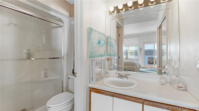 bathroom featuring vanity, a shower with shower door, and toilet