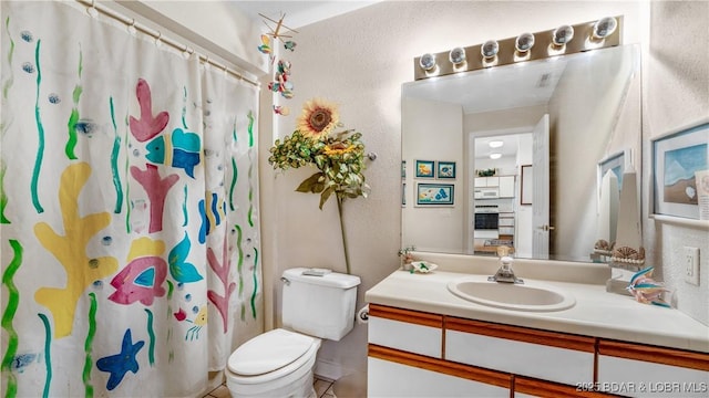 bathroom featuring vanity, curtained shower, and toilet