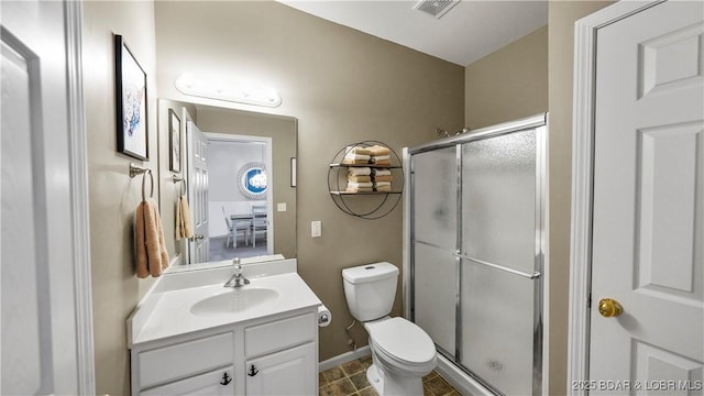 bathroom featuring tile patterned flooring, vanity, toilet, and a shower with shower door