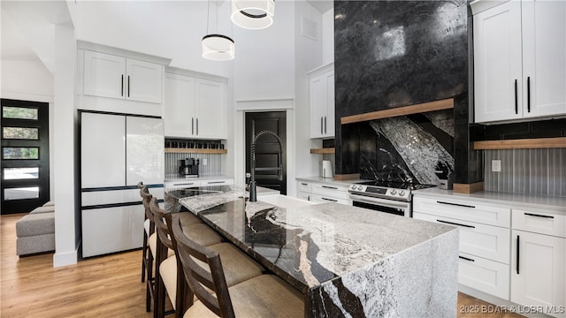 kitchen with electric stove, backsplash, fridge, and white cabinets