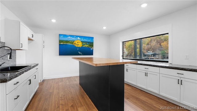 kitchen with sink, white cabinetry, wooden counters, a center island, and light wood-type flooring