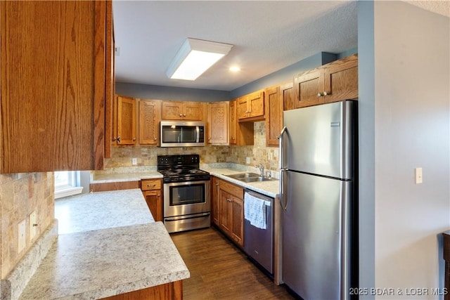 kitchen featuring appliances with stainless steel finishes, sink, dark wood-type flooring, and backsplash