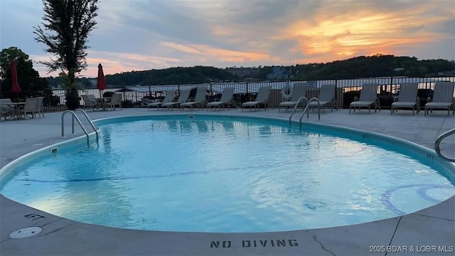 pool at dusk with a patio area