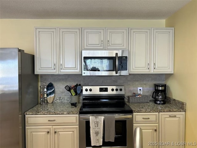 kitchen featuring white cabinetry, stainless steel appliances, tasteful backsplash, a textured ceiling, and dark stone counters