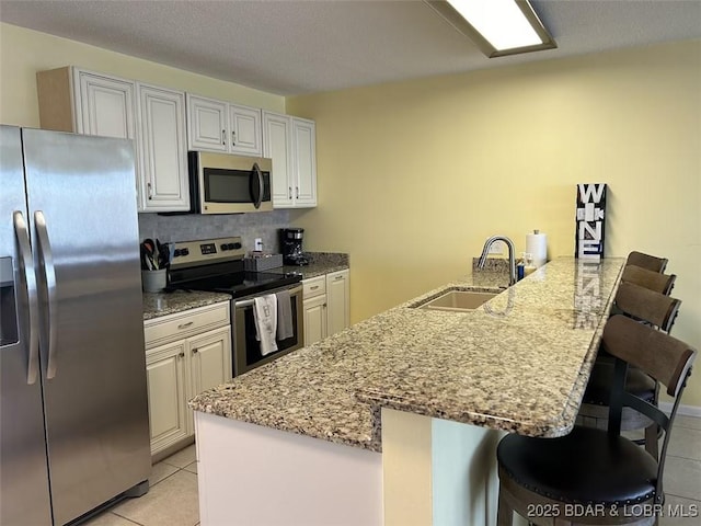 kitchen with appliances with stainless steel finishes, a breakfast bar, sink, and white cabinets