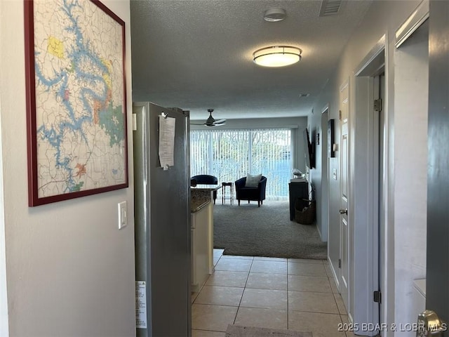 corridor with light carpet and a textured ceiling