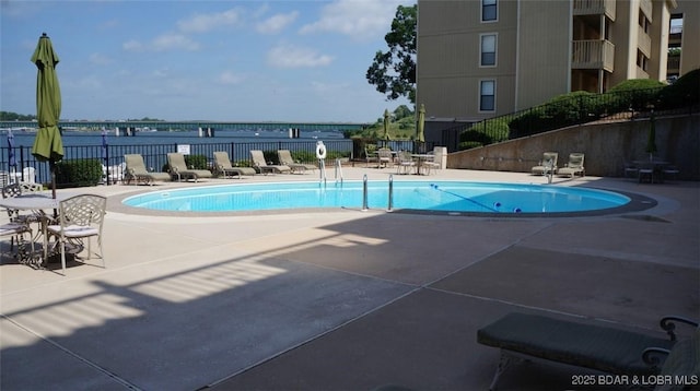 view of swimming pool with a patio and a water view