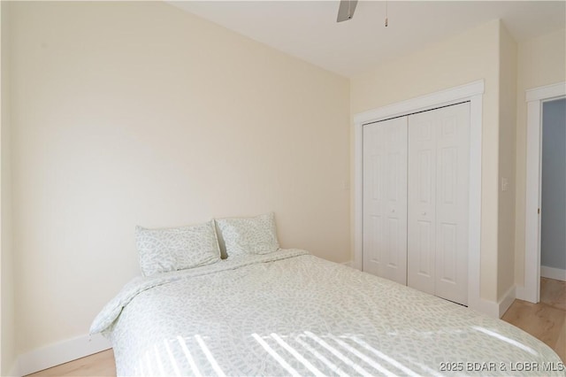 bedroom with a ceiling fan, a closet, light wood-style flooring, and baseboards