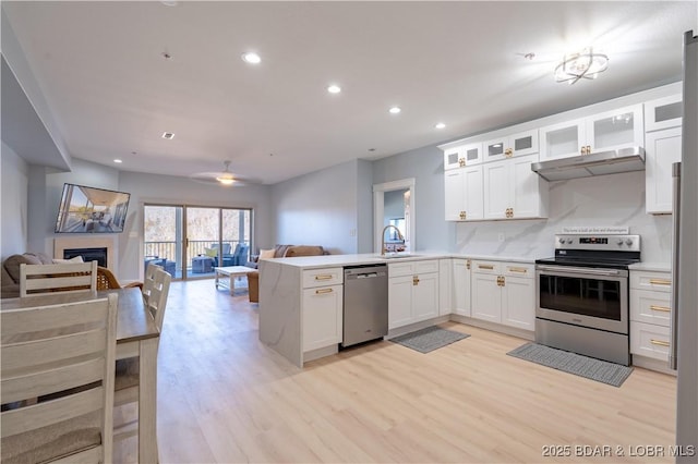 kitchen featuring open floor plan, appliances with stainless steel finishes, a sink, and under cabinet range hood