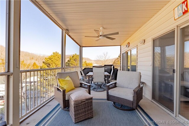 sunroom / solarium with a mountain view and ceiling fan