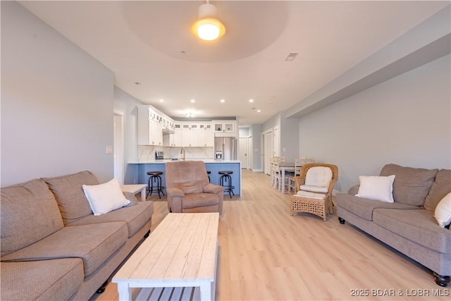 living area with light wood-type flooring and recessed lighting