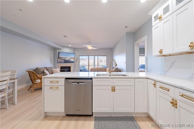 kitchen with sink, light hardwood / wood-style flooring, dishwasher, kitchen peninsula, and white cabinets