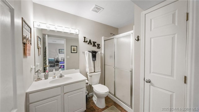 bathroom with vanity, a shower with shower door, and toilet