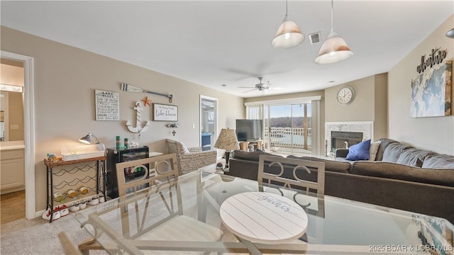 living room with ceiling fan, light colored carpet, and a fireplace