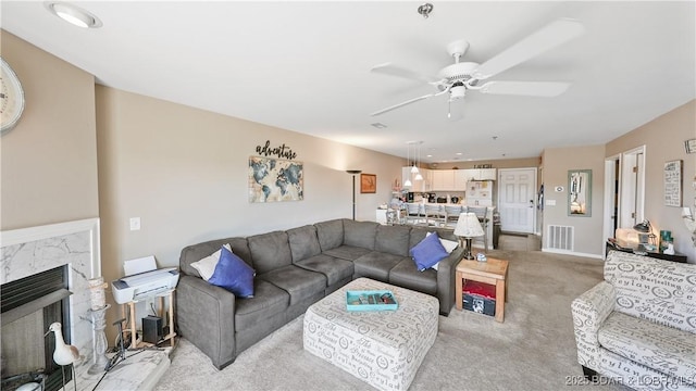 carpeted living room with a fireplace and ceiling fan