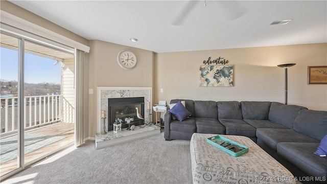 living area featuring carpet flooring, a ceiling fan, visible vents, and a fireplace