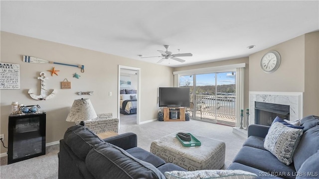 living area with a premium fireplace, light carpet, ceiling fan, and baseboards