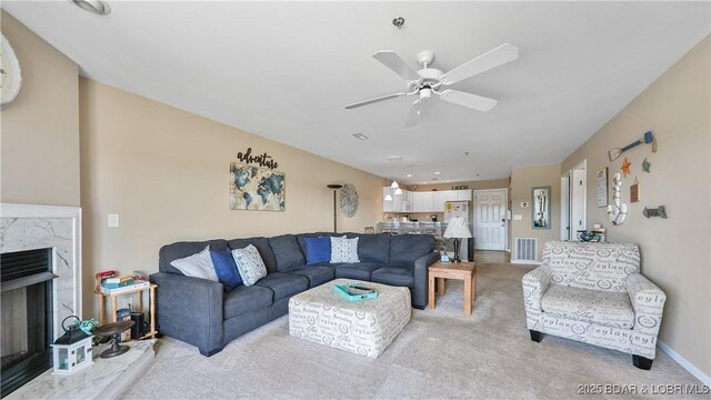 living room with a ceiling fan, visible vents, a fireplace, baseboards, and light carpet