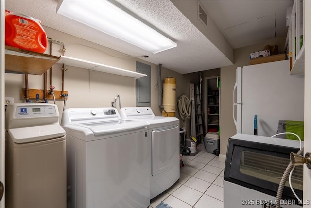 laundry area with independent washer and dryer and light tile patterned floors