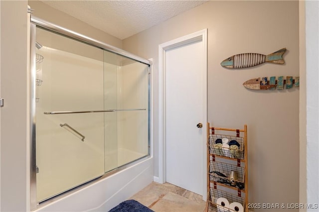 bathroom with combined bath / shower with glass door and a textured ceiling