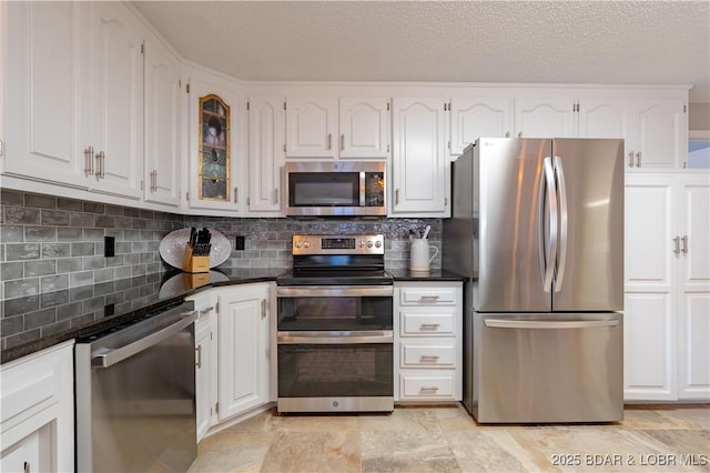 kitchen with appliances with stainless steel finishes, white cabinets, a textured ceiling, and decorative backsplash