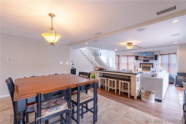 dining room with ceiling fan, a textured ceiling, and a fireplace