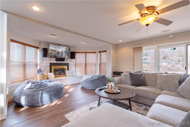 living room featuring hardwood / wood-style floors, a stone fireplace, and ceiling fan