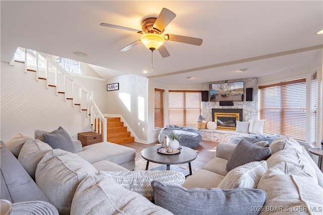 living room featuring ceiling fan, a fireplace, and light hardwood / wood-style flooring