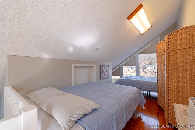 bedroom with dark wood-type flooring, lofted ceiling, and a textured ceiling