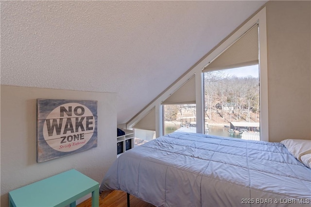 bedroom featuring lofted ceiling, hardwood / wood-style floors, and a textured ceiling