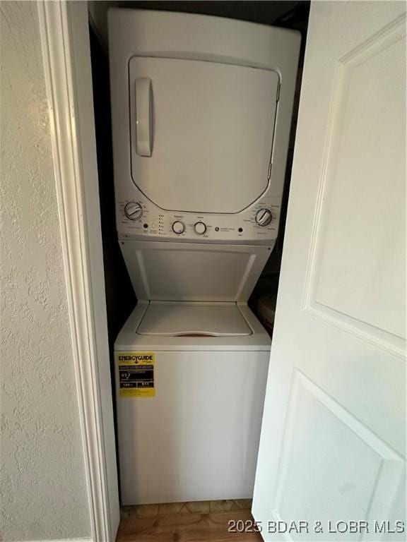 laundry room with stacked washer and clothes dryer and wood-type flooring