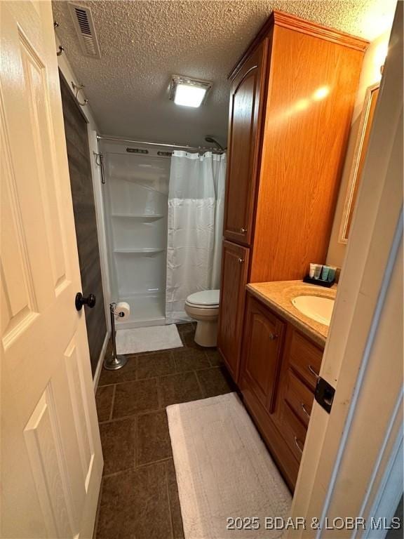 bathroom with vanity, curtained shower, a textured ceiling, and toilet