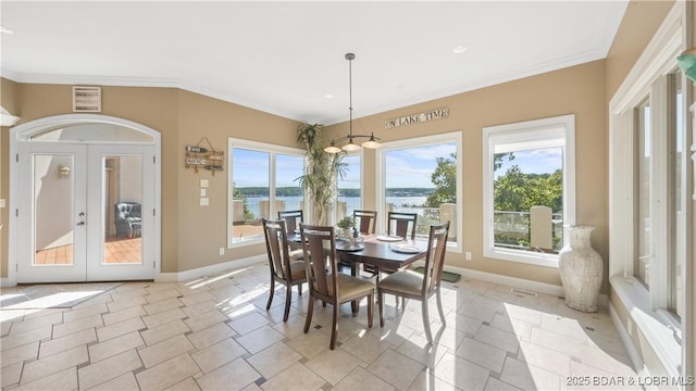 tiled dining room with a water view, crown molding, and french doors