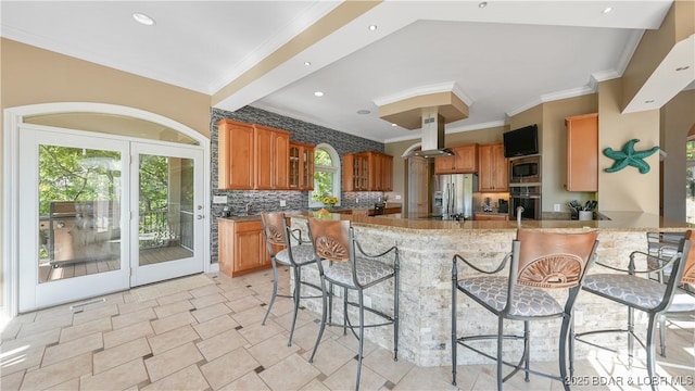 kitchen featuring island exhaust hood, appliances with stainless steel finishes, a breakfast bar area, and kitchen peninsula