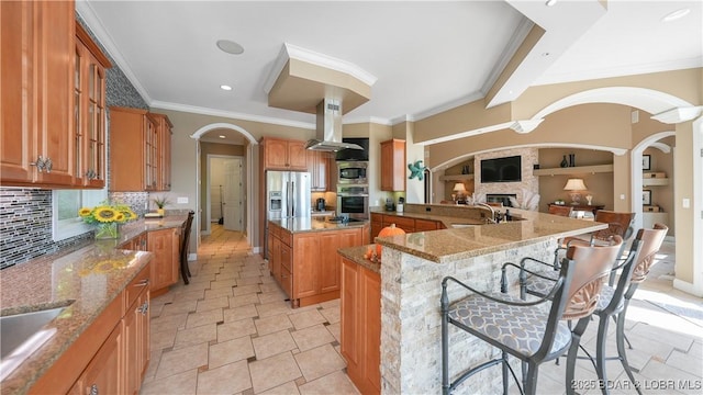 kitchen featuring a breakfast bar, stainless steel appliances, light stone countertops, a kitchen island, and built in shelves