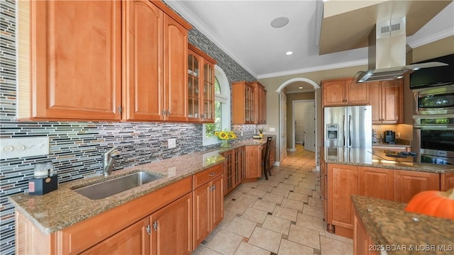 kitchen with island range hood, sink, stainless steel appliances, crown molding, and light stone countertops