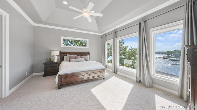 carpeted bedroom with crown molding, a water view, ceiling fan, and a tray ceiling