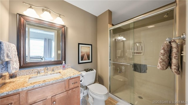 bathroom featuring an enclosed shower, vanity, and toilet